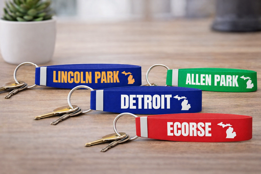 Keychains with 'Lincoln Park', 'Allen Park', 'Detroit', and 'Ecorse' text on a wooden surface.
